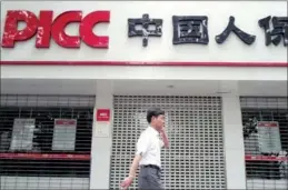  ?? ZHEN HUAI / FOR CHINA DAILY ?? A man walks past a PICC outlet in Nanjing, capital of Jiangsu province.