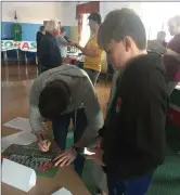  ??  ?? Cork City fans Kevin Walsh and Tim O’Keeffe get their hands on the FAI Cup, while club captain John Dunleavy signs a poster for a young supporter at the FORAS Roadshow in Fermoy.