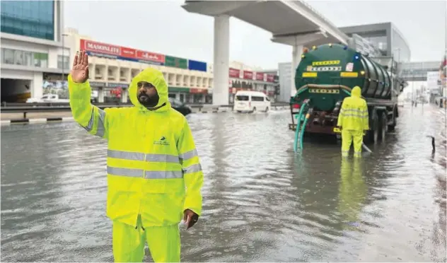  ?? WAM ?? ↑
Dubai Municipali­ty workers clean a road after rain on Friday.