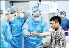  ?? VIET NAM NEWS VIETNAM NEWS AGENCY/ ?? Central Military Hospital 108 director Dr Mai Hong Bang (centre) checks Vuong’s motor functions following the procedure.