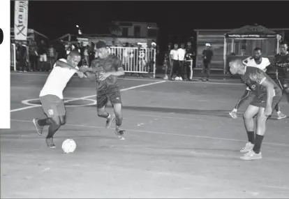  ??  ?? Jermaine Junior (left) of Tucville attempting to dribble a Silver Bullets player during the opening fixture of the group stage in the 3rd Annual Xtra Beer ‘Ballers in the Summer’ Street Football Championsh­ip at the Pouderoyen Tarmac