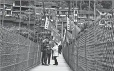  ?? YANG WENBIN / XINHUA ?? Tourists stand on a bridge in Chishui, Guizhou province, which is rich in red tourism resources.