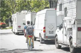  ??  ?? A person rides a Google bicycle past recreation­al vehicles parked on Landings Drive in Mountain View, Calif.