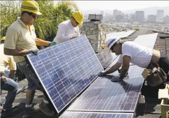  ?? Reed Saxon / AP 2010 ?? Installers assemble solar electrical panels on the roof of a Southern California home in 2010. A push is on in the state to generate at least 50 percent of electricit­y from renewable resources.