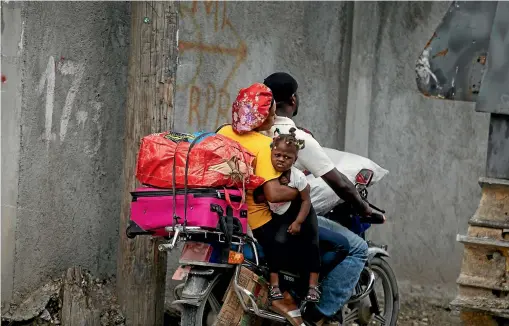  ?? AP ?? Residents travel on a motorbike as they flee their home to avoid clashes between armed gangs, in the Croix-des-Mission neighbourh­ood of Port-au-Prince.