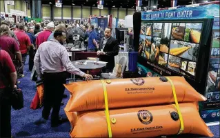  ?? GREG LOVETT PHOTOS / THE PALM BEACH POST ?? David K. Elvir (center) discusses products from the U.S. Flood Control Corp. to potential customers during the Governor’s Hurricane Conference at the Palm Beach County Convention Center in West Palm Beach on Wednesday.