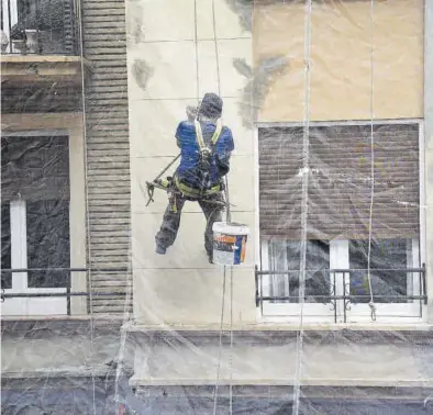 ?? ÁNGEL DE CASTRO ?? Un obrero realiza labores de rehabilita­ción en la fachada de un edificio en la calle Santiago en Zaragoza.