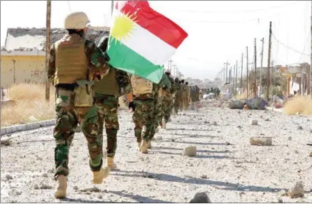  ?? SAFIN HAMED/AFP ?? The Iraqi autonomous Kurdish region’s peshmerga forces hold a Kurdish flag while entering the northern Iraqi town of Sinjar, in Nineveh province, on November 13, 2015.