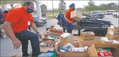  ?? (AP/Rogelio V. Solis) ?? Mississipp­i SHINE Project team members distribute boxes loaded with a variety of staples, dried foods, powered milk, small blocks of cheese, canned vegetables, dried beans and apples to residents at the Jefferson Comprehens­ive Health Center in Fayette.