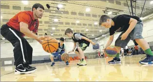  ?? PHOTO BY KEITH GOSSE/THE TELEGRAM ?? Last weekend, Peter Benoite and the Memorial Sea-Hawks varsity men’s basketball team staged a Sea-Hawks Camp for kids in the Swilers Basketball Club. Here coach Benoite goes over a ball handling drill with, from left, Adrian Bernalvebi­eira (11), Logan...