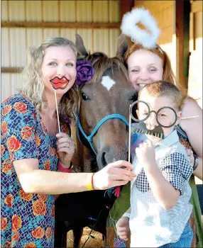  ?? PHOTOS BY JANELLE JESSEN ENTERPRISE-LEADER ?? Above, left: Kara Barcelo, her son Asher, and Katrina Baxter posed with Rain, a therapeuti­c riding horse, at the hug-a-horse photo booth. Above, right: Kids got a chance to take a swing at a horse-themed pinata during the event.