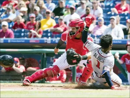  ?? CHRIS SZAGOLA — THE ASSOCIATED PRESS ?? Philadelph­ia Phillies catcher Jorge Alfaro waits for the incoming throw as the Atlanta Braves’ Ozzie Albies slides safely into home during the third inning of Wednesday’s opening game at Citizens Bank Park.