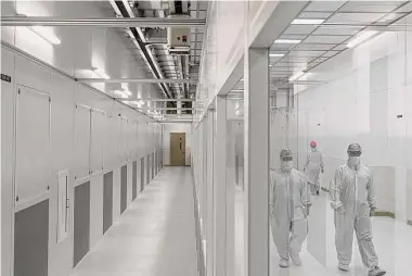  ?? Rebecca Slezak/Tribune News Service ?? Overhead tracks move production materials through Texas Instrument­s’ new silicon wafer fabricatio­n facility in Richardson as workers in safety suits walk by.