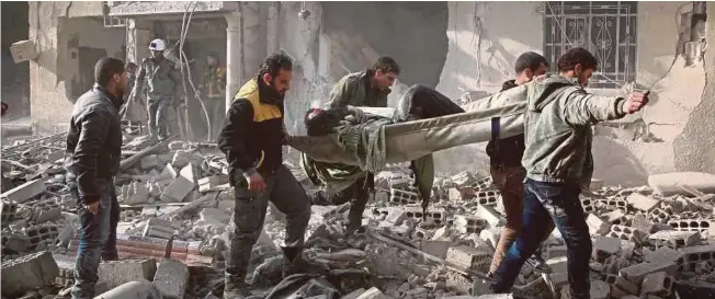  ?? AFP PIC ?? Members of the Syrian civil defence forces known as White Helmets evacuating a victim of an air strike in the rebelheld enclave of Arbin in Eastern Ghouta near Damascus on Thursday.