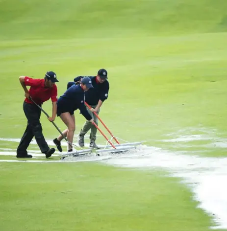  ?? NATHAN DENETTE/THE CANADIAN PRESS ?? Workers push the water off the 16th fairway after a two-hour rain delay Thursday. Play was suspended for darkness with 15 players still on the course.