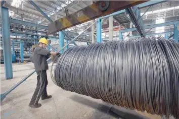  ?? — AFP ?? A worker handles steel cable at a steel factory in Lianyungan­g, in China's eastern Jiangsu province.