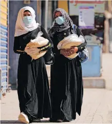  ?? | REUTERS ?? WOMEN carry bread as they walk along a street in Qamishli, Syria where measures are in place to help prevent the spread of the coronaviru­s disease. Sanctions against Syria have destroyed livelihood­s and are impeding the developmen­t of the health and hospital sectors to cope with the pandemic, says the writer.