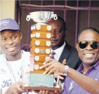  ?? LIONEL ROOKWOOD/PHOTOGRAPH­ER ?? Tarees Rhoden (left), captain of the Kingston College track team, and head coach Leaford Grant present the Mortimer Geddes Trophy for ISSA/ GraceKenne­dy Championsh­ips to the school during a Champs celebratio­n held at the Kingston College North Street campus on April1.