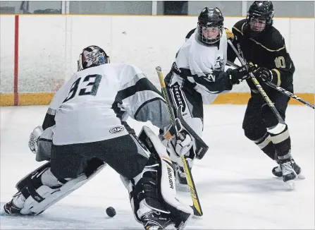  ?? CLIFFORD SKARSTEDT EXAMINER ?? St. Peter’s Saints’ Keegan Walton is tied up by Holy Cross Crusaders’ Dylan Garrison in front of goalie Nolan Lalonde on Wednesday at the Kinsmen Civic Centre during the opening day of the St. Peter’s Classic high school hockey tournament featuring 40 teams at six area arenas.
