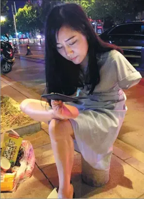  ?? WEI ZHENWEI / FOR CHINA DAILY ?? Yang Li uses a smartphone on the street of Bengbu, Anhui province.