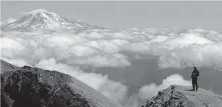  ?? Ted S. Warren, The Associated Press ?? Peter Haley stands on the crater rim of Mount St. Helens, with Mount Adams in the background. The eruption of the Kilauea volcano in Hawaii has geologic experts along the West Coast warily eyeing the volcanic peaks in Washington, Oregon and California,...