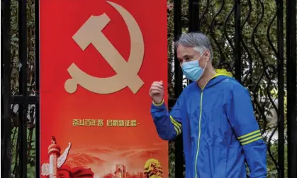  ?? Photograph: Alex Plavevski/EPA ?? A masked man passes by a Chinese Communist party poster in Shanghai, where a number of residentia­l communitie­s have been put under lockdown.