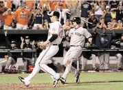  ?? Patrick Semansky / Associated Press ?? The O’s Jim Johnson, left, covers home after a wild pitch, but the Yankees’ Brendan Ryan scores anyway.