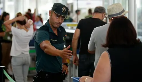  ?? ?? A civil guard officer gestures as passengers pass the security control at the Barcelona airport in Prat Llobregat, Spain, Aug. 14, 2017.