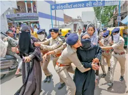  ?? — PTI ?? Police personnel detain people during their protest demanding arrest of former BJP spokespers­on Nupur Sharma over her remarks against Prophet Muhammad, in Ahmedabad on Sunday.
