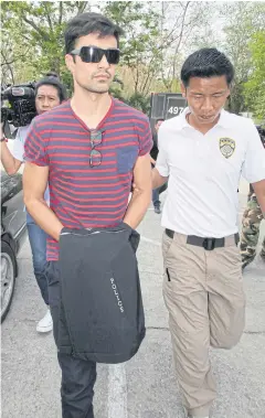  ?? APICHIT JINAKUL ?? Police escort Diego Fernado Gonzale Rojas, a Colombian, to the Criminal Court to be detained for allegedly posting defamatory messages online. Mr Rojas, also charged with working illegally as a model, was later released on bail.