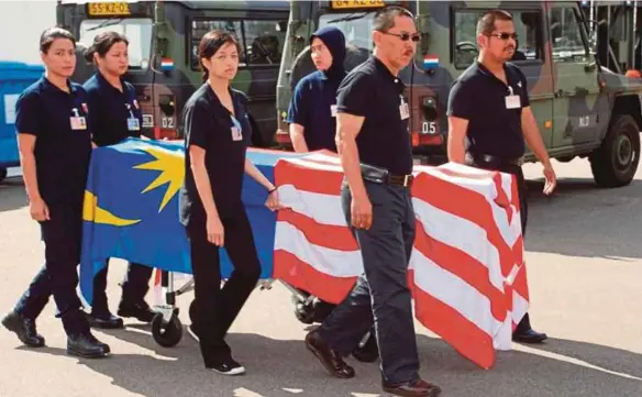  ??  ?? Datuk Dr Mohd Shah Mahmood (second from right) and his forensic unit team members carrying the remains retrieved from the crash site of Malaysia Airlines Flight MH17 in Hilversum, The Netherland­s.