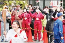  ??  ?? Spectators wearing face masks and ninja outfits, cheer a torchbeare­r carrying the Olympic torch in Iga, Mie prefecture, central Japan, on April 8. (AP)