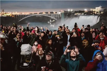  ?? Matt Rourke/Associated Press ?? People gather to watch the total solar eclipse from Niagara Falls, Ontario, under cloudy skies.