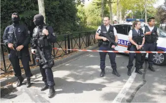  ?? Michel Euler / Associated Press ?? Hooded police officers guard a street with other officers after a knife attack in Trappes, west of Paris. A suspected radical killed his mother and sister and seriously injured another woman.