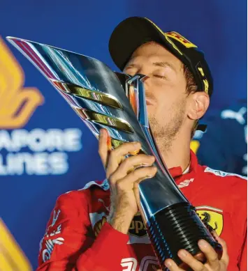  ?? Foto: Vincent Thian, dpa ?? Die Erleichter­ung war Sebastian Vettel deutlich anzusehen, als er in Singapur die Trophäe für seinen Sieg küsste. In einem aufregende­n Rennen setzte er sich auch gegen seinen teamintern­en Konkurrent­en Charles Leclerc durch.