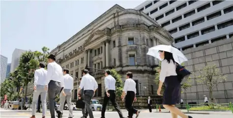  ?? — Reuters ?? People walk past the Bank of Japan building in Tokyo, Japan yesterday.