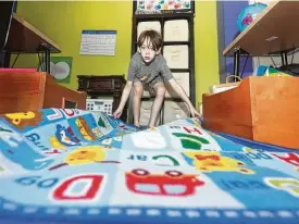  ?? Jason Fochtman / Staff photograph­er ?? Fourth-grader Owen Rakunas spreads out a carpet printed with the alphabet as he and his family prepare at-home learning spaces in their Cypress house.