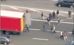  ??  ?? Migrants make a quick dash for lorries stuck in traffic in Calais during the industrial action