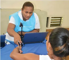  ?? Photo: CI News ?? Fijian Elections Office operations assistant Mereseini Vosa helps a potential voter with her registrati­on.