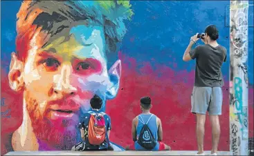  ?? Picture: AFP/JOSEP LAGO ?? POPULAR ATTRACTION: Fans look at a mural portraying Argentine forward Lionel Messi in Barcelona. The South American football star plays for Barcelona