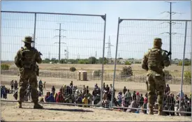  ?? ANDRES LEIGHTON - THE ASSOCIATED PRESS, FILE ?? Migrants wait in line adjacent to the border fence under the watch of the Texas National Guard to enter into El Paso, Texas, Wednesday, May 10, 2023.