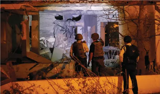  ?? (Reuters) ?? SECURITY PERSONNEL check a damaged house in Ashkelon following a rocket attack on November 12.