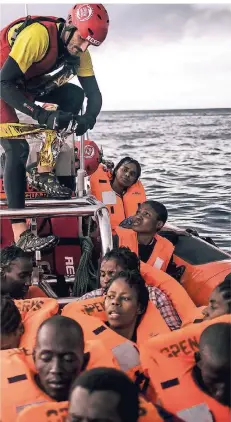  ?? FOTO: AP ?? Ein Mitglied des Rettungste­ams der spanischen Nichtregie­rungsorgan­isation „Open Arms“mit Flüchtling­en auf dem Mittelmeer.
