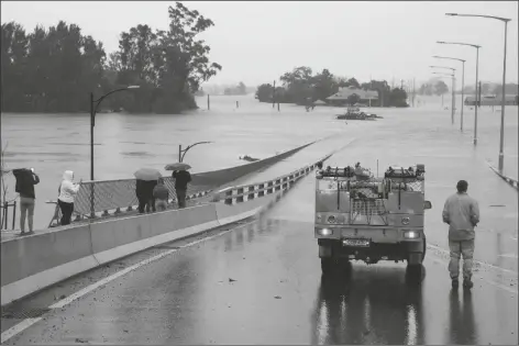  ?? MARK BAKER/AP ?? AN EMERGENCY VEHICLE BLOCKS ACCESS to the flooded Windsor Bridge on the outskirts of Sydney, Australia, on Monday. More than 30,000 residents of Sydney and its surrounds have been told to evacuate or prepare to abandon their homes on Monday as Australia’s largest city braces for what could be its worst flooding in 18 months.