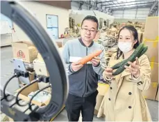  ?? AFP ?? Employees in China show vegetables for sale during a live broadcast for online customers.