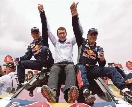  ?? AFP PIC ?? Peugeot driver Carlos Sainz (right) and co-driver Lucas Cruz (left) celebrate their winning the Dakar Rally with team manager Bruno Famin (centre) on Saturday.