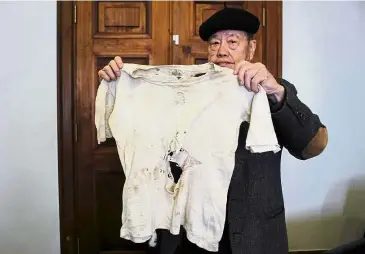  ?? — AFP ?? Tragic reminder: Pan holding up a T-shirt worn by his father when he was executed by firing squad in 1947.