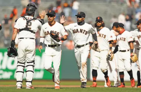  ?? Scott Strazzante / The Chronicle ?? LaMonte Wade Jr. greets catcher Curt Casali as he follows Mauricio Dubon off the field after the Giants’ 40 win over Colorado.