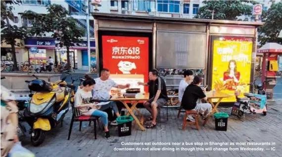  ?? — IC ?? Customers eat outdoors near a bus stop in Shanghai as most restaurant­s in downtown do not allow dining in though this will change from Wednesday.