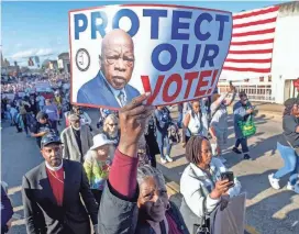  ?? MICKEY WELSH/ADVERTISER ?? Rochelle Bender carries a Protect Our Vote sign as she crosses the Edmund Pettus Bridge in Selma on Sunday during the 59th anniversar­y celebratio­n of the Bloody Sunday March.